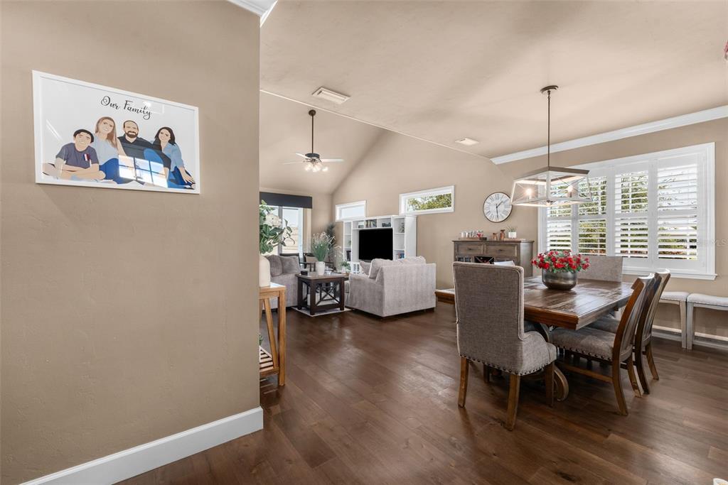 A dining area and living room with hardwood floors, vaulted ceilings, and plantation shutters — 24674 SW 19TH PLACE, NEWBERRY, FL