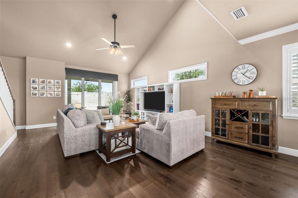 A living room features a vaulted ceiling, hardwood floors, a sectional sofa, and a media console — 24674 SW 19TH PLACE, NEWBERRY, FL