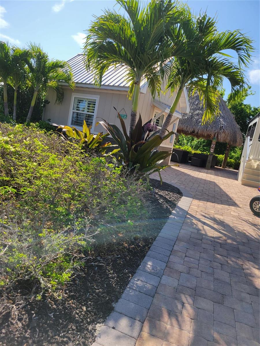 A small cottage with a metal roof, palm trees, and a thatched-roof tiki hut outside — 628 SW 35th, Okeechobee FL 34974, OKEECHOBEE, FL