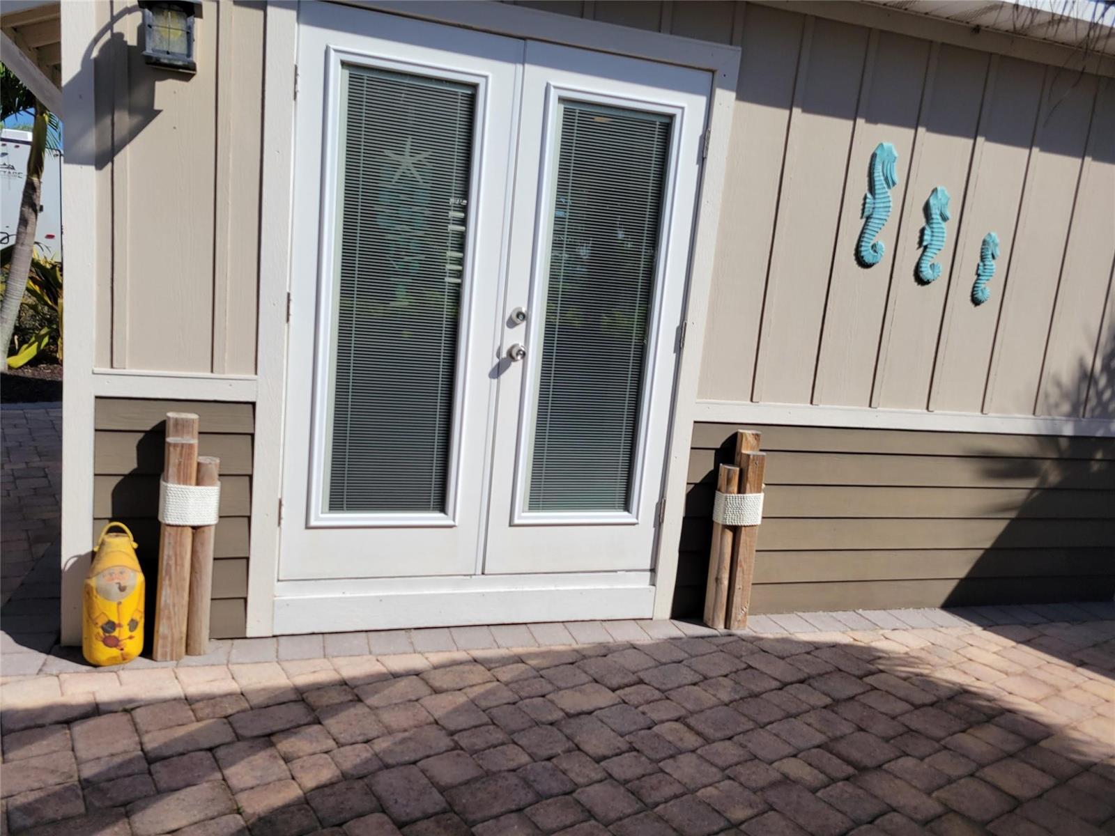 A beige exterior wall features double glass doors, decorative seahorses, and wooden posts on pavers — 628 SW 35th, Okeechobee FL 34974, OKEECHOBEE, FL