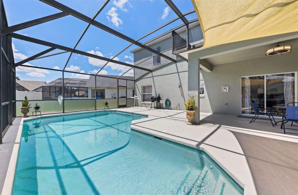 A swimming pool with a screened enclosure and a covered patio area — 4817 CUMBRIAN LAKES DRIVE, KISSIMMEE, FL