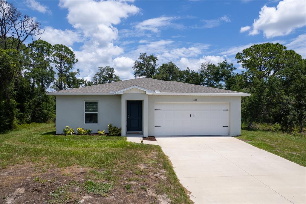 A single-story house with a white stucco exterior, a two-car garage, and a front entrance — 15530 MAYNARD AVENUE, PORT CHARLOTTE, FL