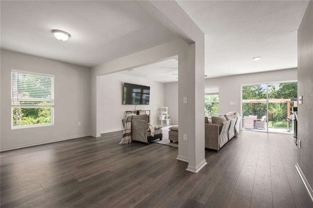 A living area with gray wood-look flooring, neutral walls, and a sliding glass door — 15530 MAYNARD AVENUE, PORT CHARLOTTE, FL