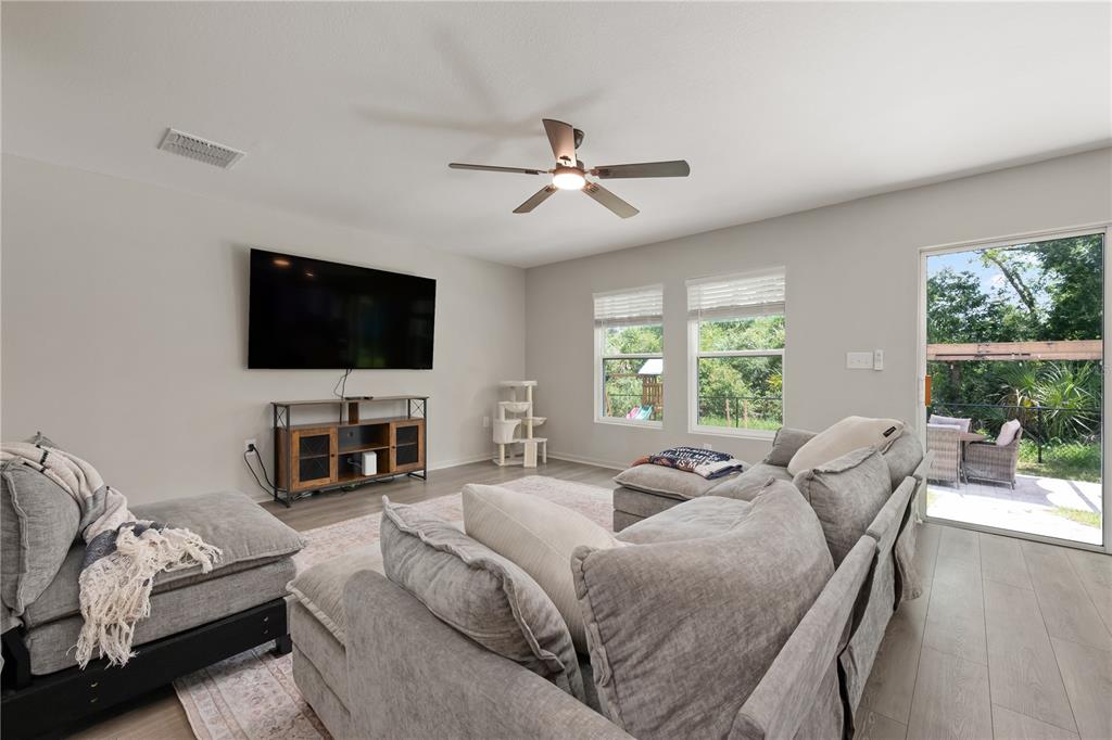 A living room features a large sectional sofa, a wall-mounted television, and a sliding glass door — 15530 MAYNARD AVENUE, PORT CHARLOTTE, FL