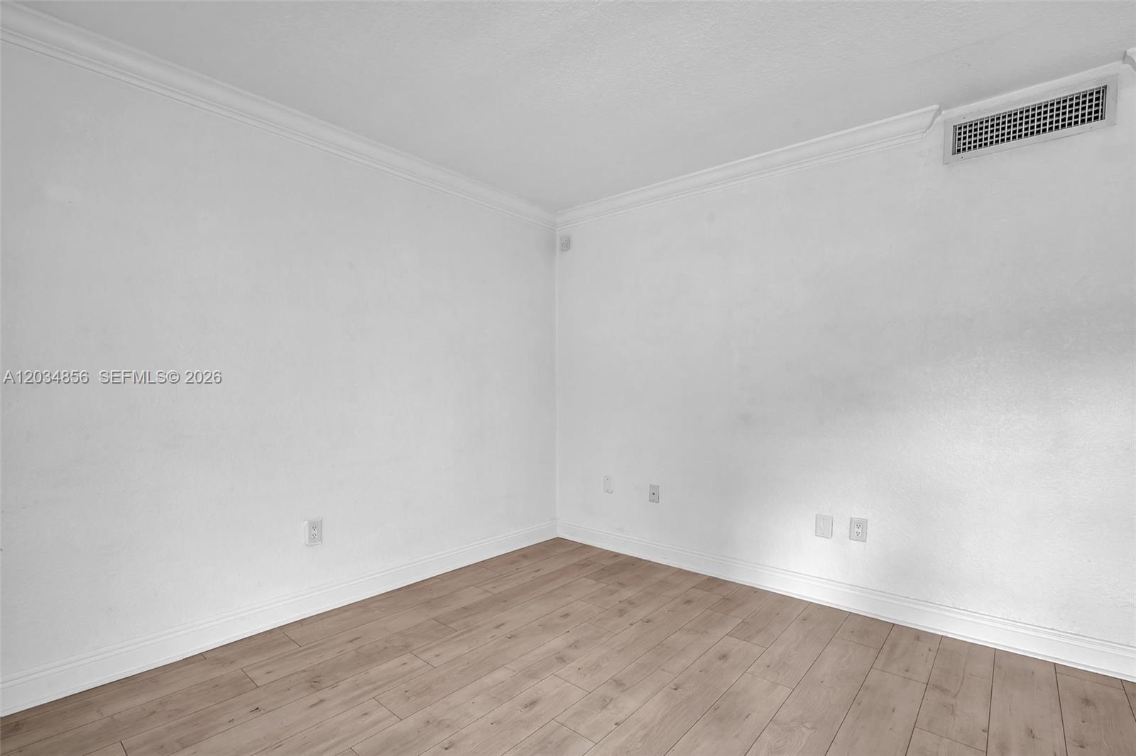 An empty room features white walls, crown molding, and light-colored wood-look flooring — 3245 Virginia St # 24, Miami FL 33133, MIAMI, FL