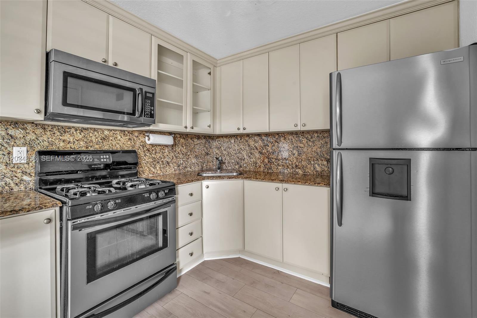 A kitchen features beige cabinets, stainless steel appliances, and speckled granite countertops — 3245 Virginia St # 24, Miami FL 33133, MIAMI, FL