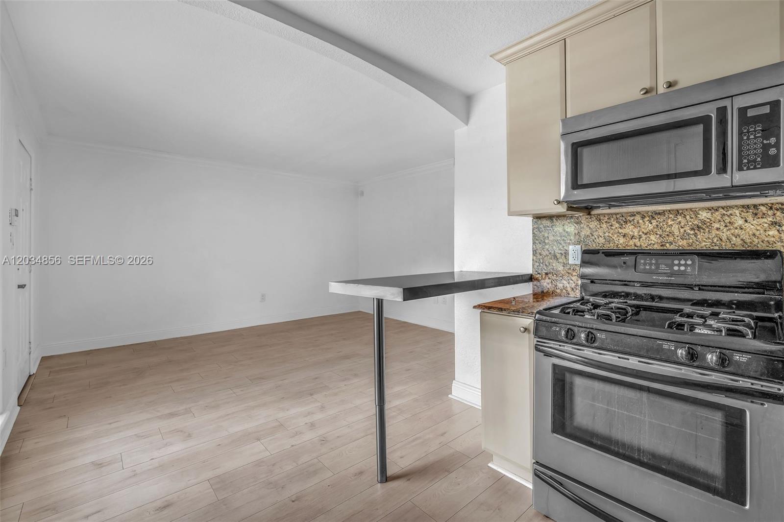 A kitchen with a stainless steel stove and microwave features a breakfast bar extension — 3245 Virginia St # 24, Miami FL 33133, MIAMI, FL