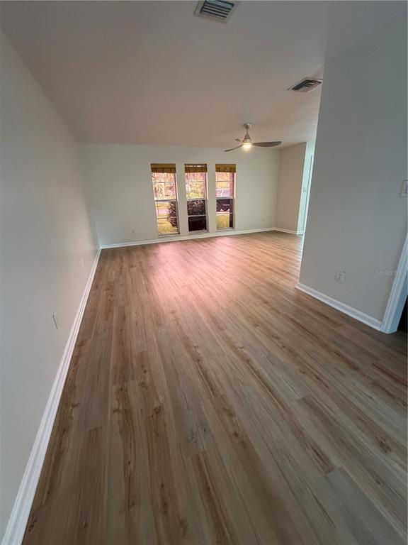 An empty room with light-colored walls, wood-look flooring, a ceiling fan, and three windows — 3024 BLOWN FEATHER LANE, MULBERRY, FL