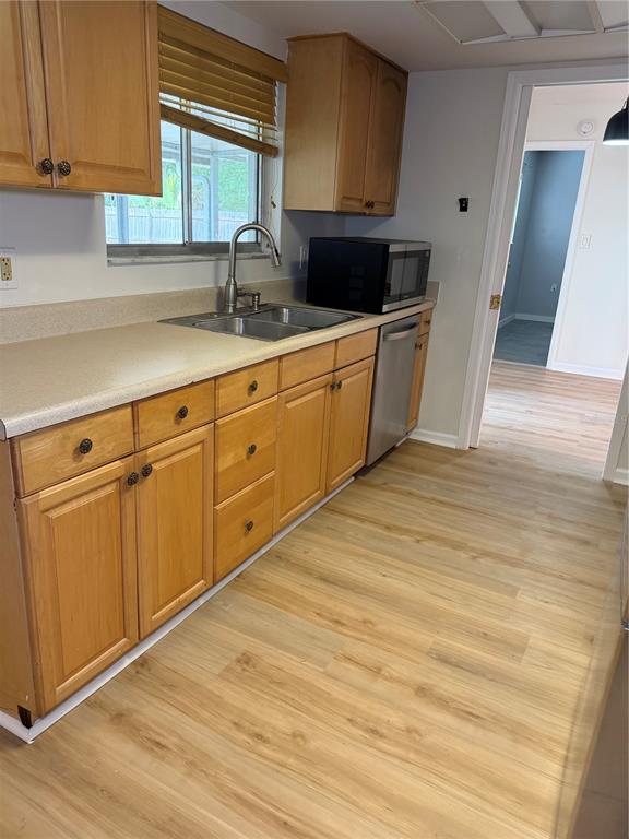 A kitchen features light wood cabinets, a stainless steel sink, and light-colored laminate flooring — 3024 BLOWN FEATHER LANE, MULBERRY, FL