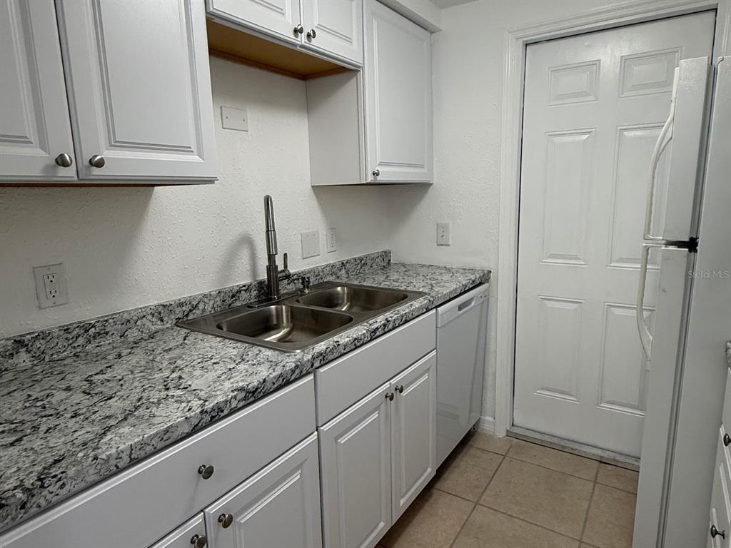 A kitchen features white cabinets, granite countertops, a double-basin sink, and a white dishwasher — 4954 BITNER STREET, NEW PORT RICHEY, FL