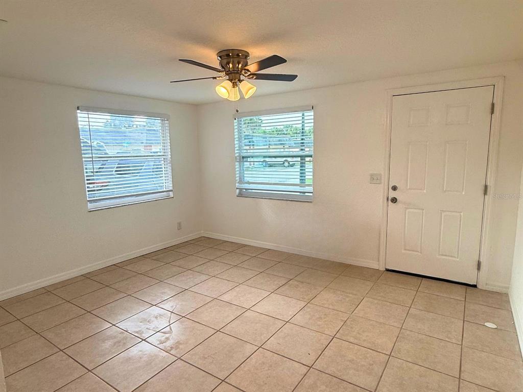 A room with light-colored tile flooring, two windows with blinds, and a ceiling fan — 4954 BITNER STREET, NEW PORT RICHEY, FL
