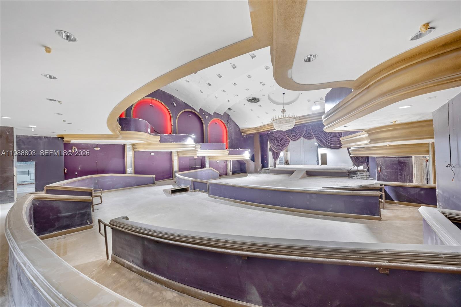 An interior view of a vacant, tiered event hall featuring purple walls and gold trim — 5445 Collins Ave, Miami Beach FL 33140, MIAMI BEACH, FL