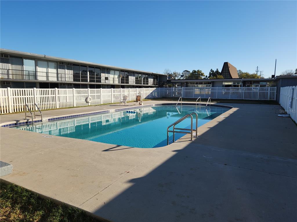 A rectangular swimming pool sits in a concrete deck enclosed by a white vinyl fence — 1202 RIDGEWOOD AVENUE, HOLLY HILL, FL