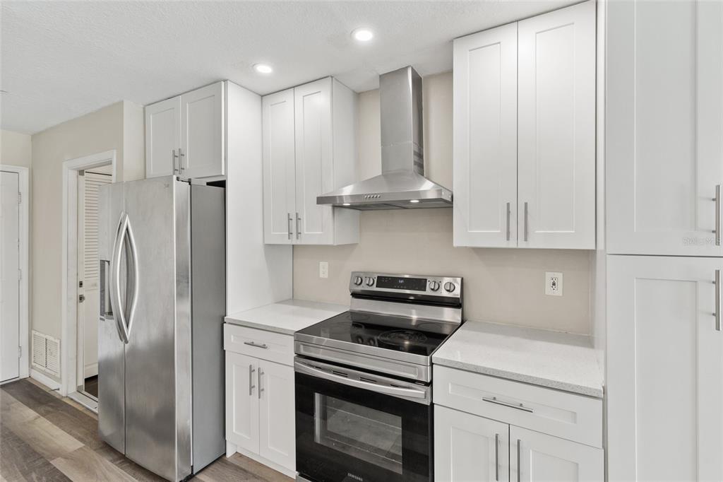 A kitchen features white shaker cabinets, stainless steel appliances, and light-colored countertops — 1009 KINGS COURT, VENICE, FL