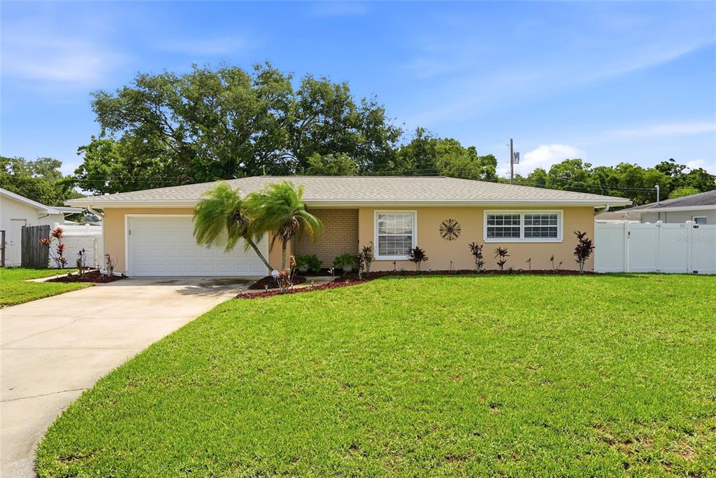 A single-story house with a beige exterior, a white garage door, and a green lawn — 1417 FAIRFIELD DRIVE, CLEARWATER, FL