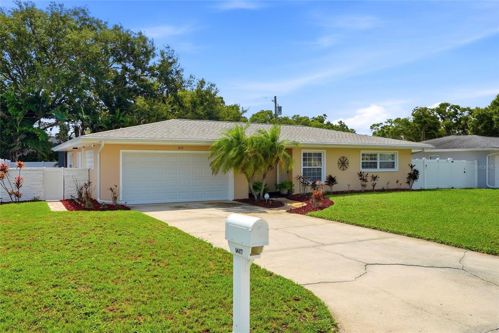 A single-story house with a beige exterior, a two-car garage, and a concrete driveway — 1417 FAIRFIELD DRIVE, CLEARWATER, FL
