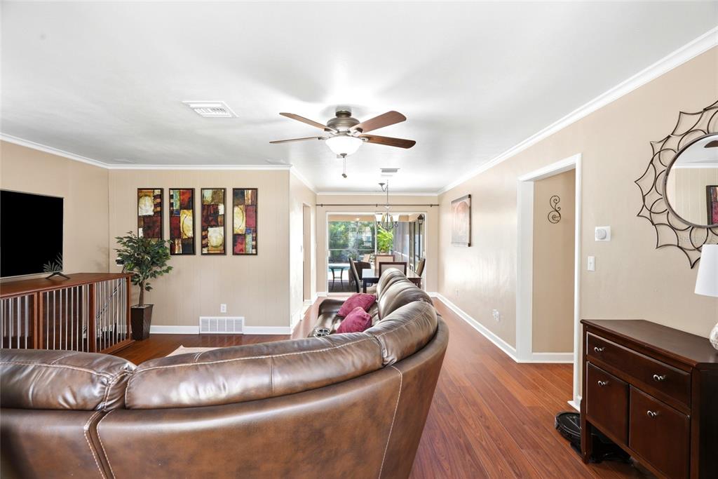 A living room features a brown leather sectional, wood flooring, and a ceiling fan — 1417 FAIRFIELD DRIVE, CLEARWATER, FL