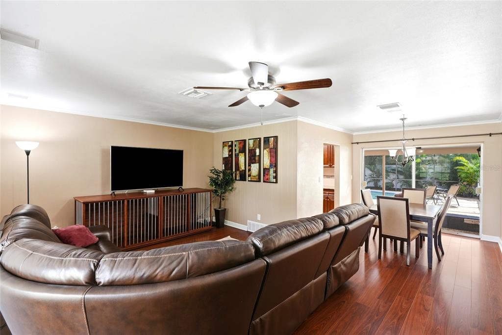 A living room with a brown leather sectional, television console, and dining area with patio access — 1417 FAIRFIELD DRIVE, CLEARWATER, FL