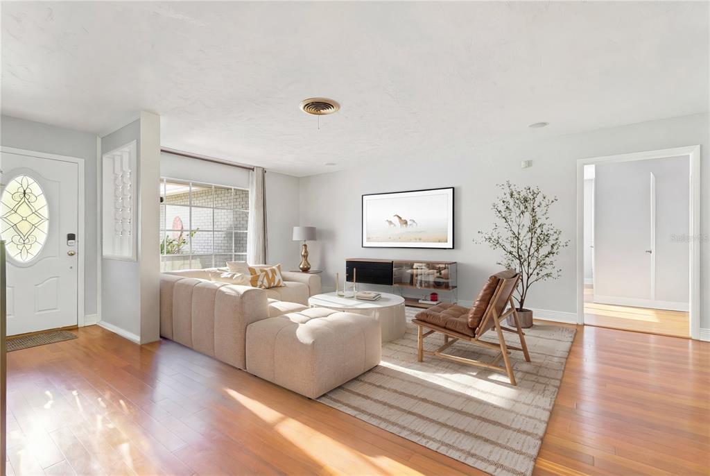 A living room features light hardwood floors, a beige sectional sofa, and a wall-mounted television — 2102 W KYRA DRIVE, TAMPA, FL