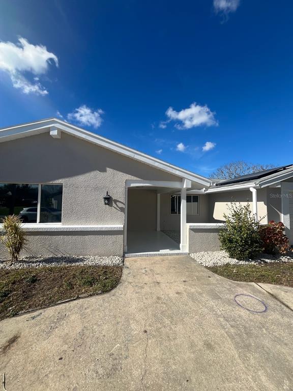 A beige, single-story house features a covered entryway, a concrete driveway, and a small garden — 3631 GRAYTON DRIVE, NEW PORT RICHEY, FL