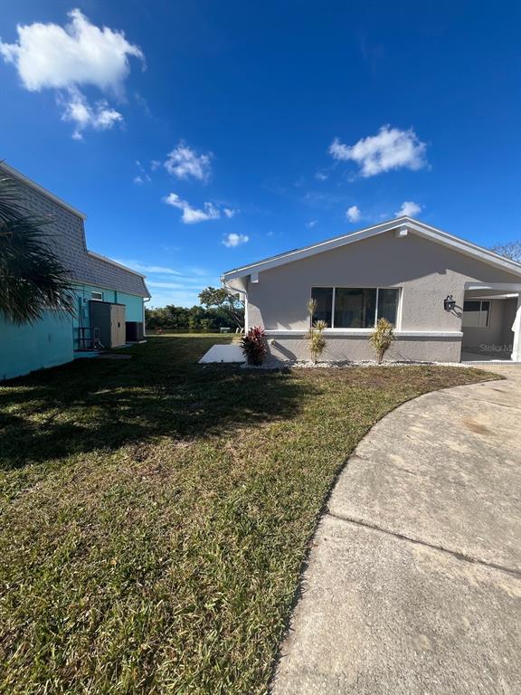 A view of the side yard and exterior of a light-colored house with a driveway — 3631 GRAYTON DRIVE, NEW PORT RICHEY, FL