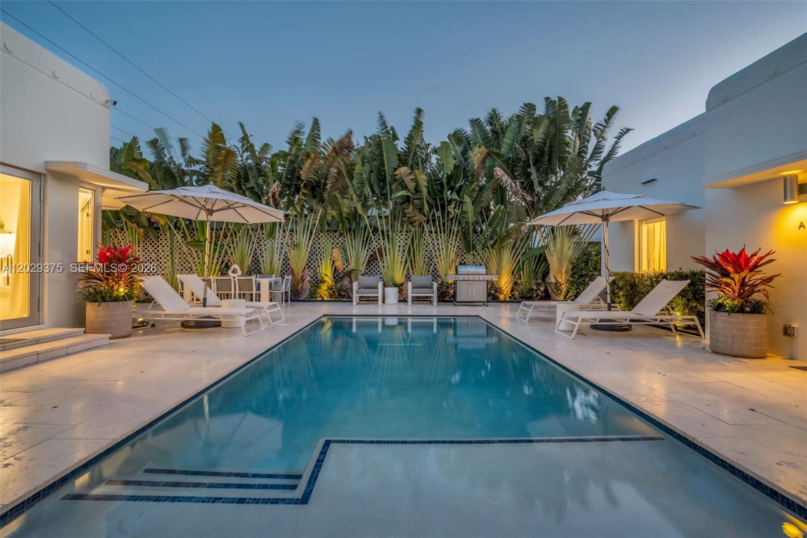 A rectangular swimming pool sits in a courtyard surrounded by lounge chairs and tropical plants — 8109 Harding Ave, Miami Beach FL 33141, MIAMI BEACH, FL