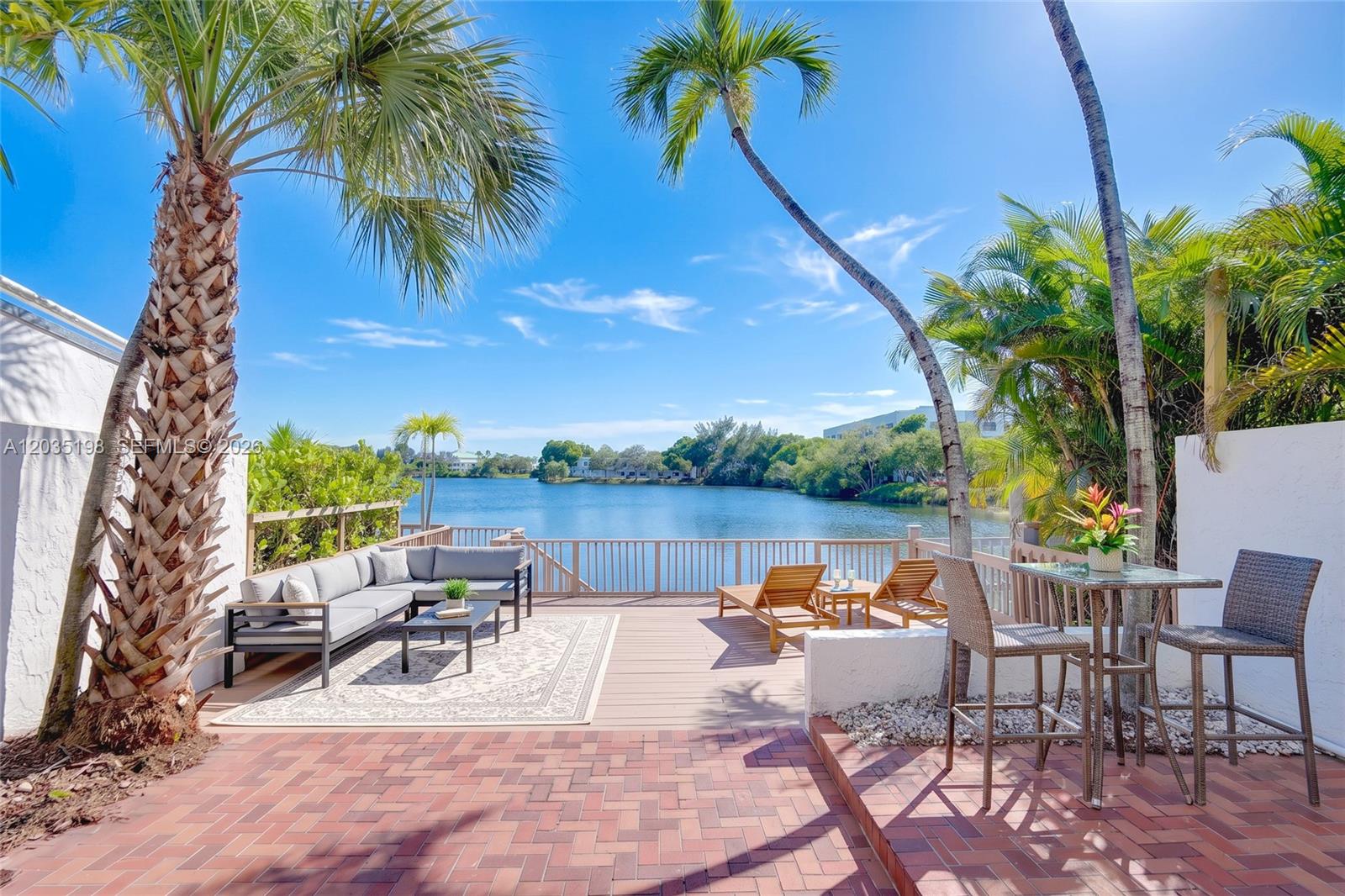 A patio with a wooden deck, outdoor seating, and a view of a lake — 5002 SW 72nd Ave, Miami FL 33155, MIAMI, FL