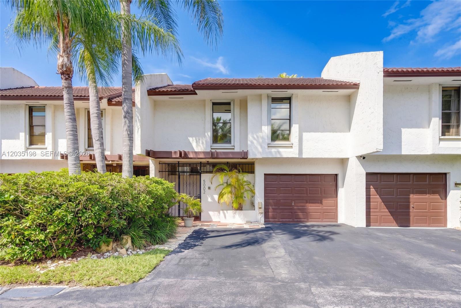 A two-story townhouse features a brown garage door, white stucco exterior, and palm trees — 5002 SW 72nd Ave, Miami FL 33155, MIAMI, FL