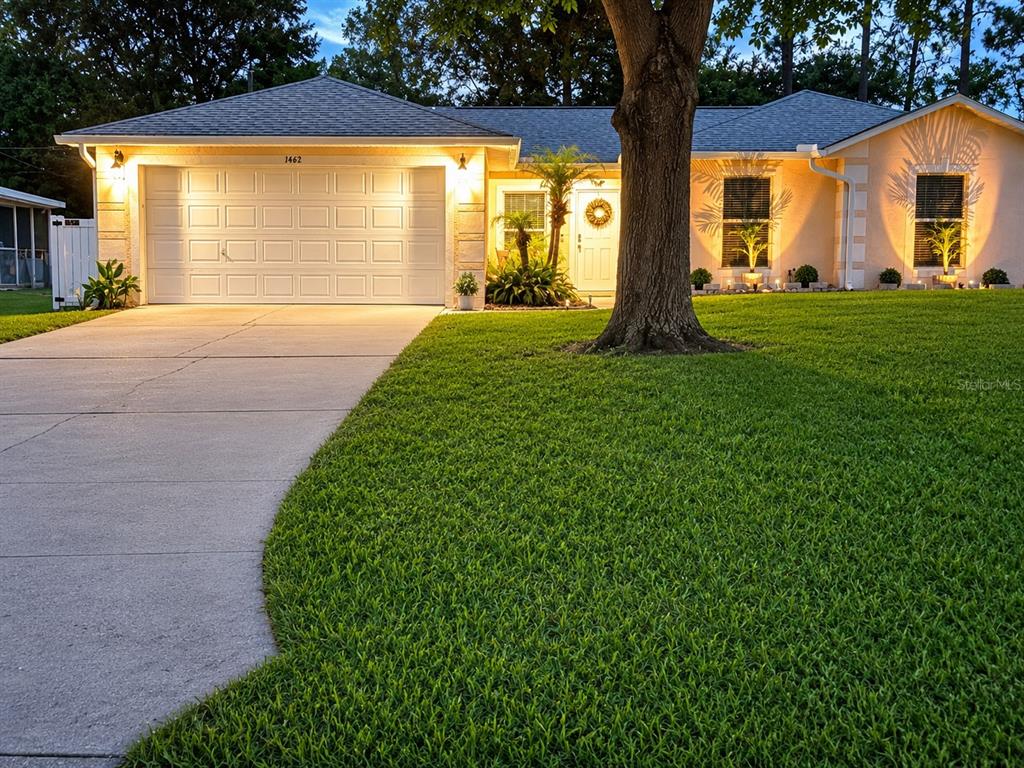 A single-story house with a white garage, a large tree, and a green lawn — 1462 ADMIRAL NIMITZ AVE, DAYTONA BEACH, FL