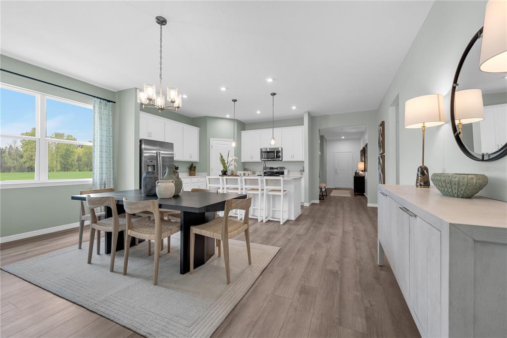 A dining area with a dark table and chairs opens into a white kitchen — 12885 TROVITA DRIVE, GRAND ISLAND, FL
