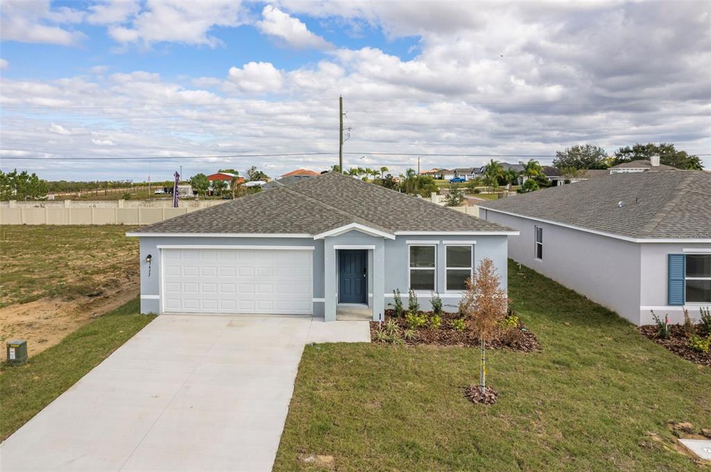 A light blue single-story house features a two-car garage and a front-facing entrance — 3477 DAHLIA DRIVE, LAKE HAMILTON, FL