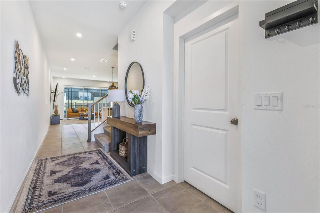 A bright entryway features a console table, a rug, and a door leading to a room — 2354 ZABALLINA PLACE, KISSIMMEE, FL