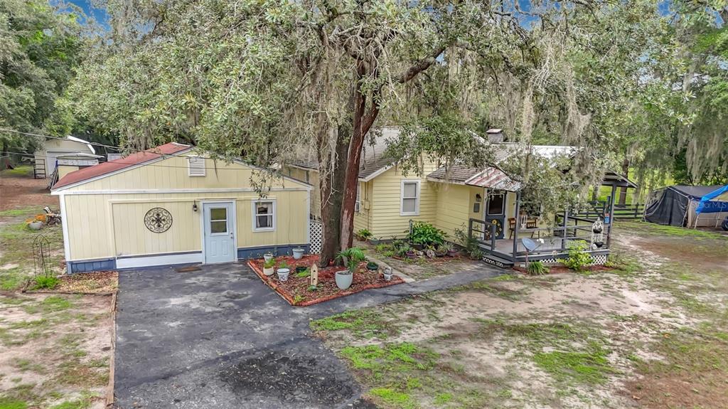 An exterior view of a yellow house with a detached garage and a covered porch — 11705 MARY LOU DRIVE, HUDSON, FL