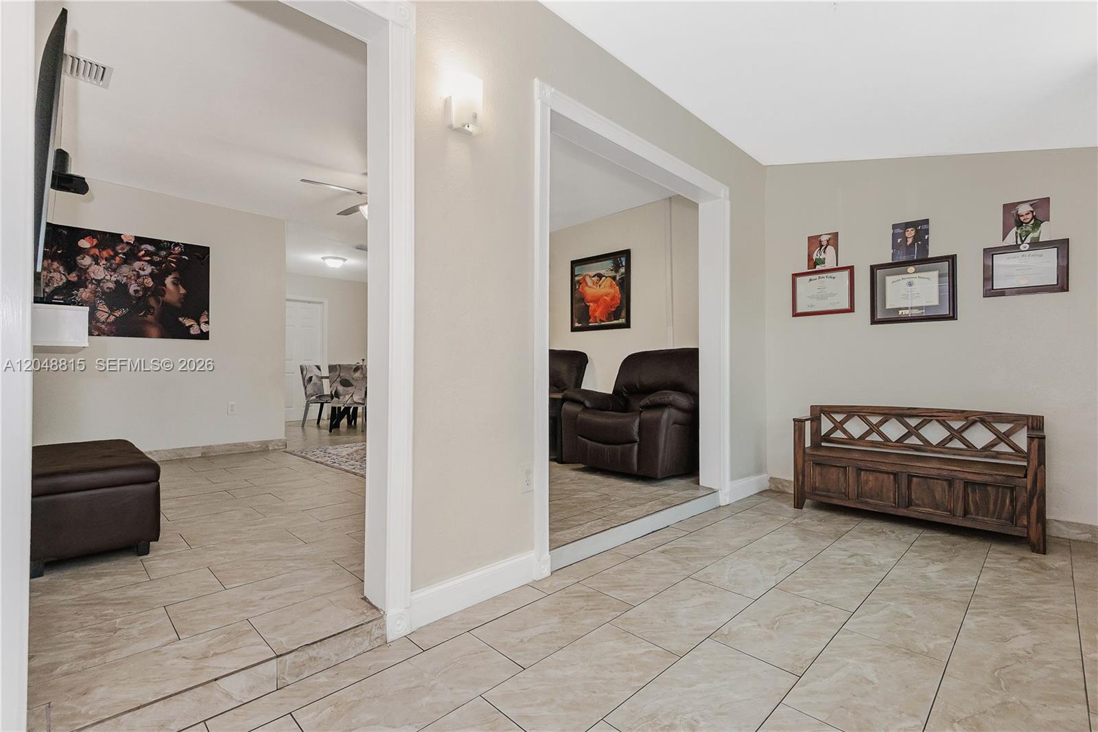 A tiled entryway features a wooden bench, wall art, and two openings into adjacent rooms — 750 NE 4th Pl, Hialeah FL 33010, HIALEAH, FL