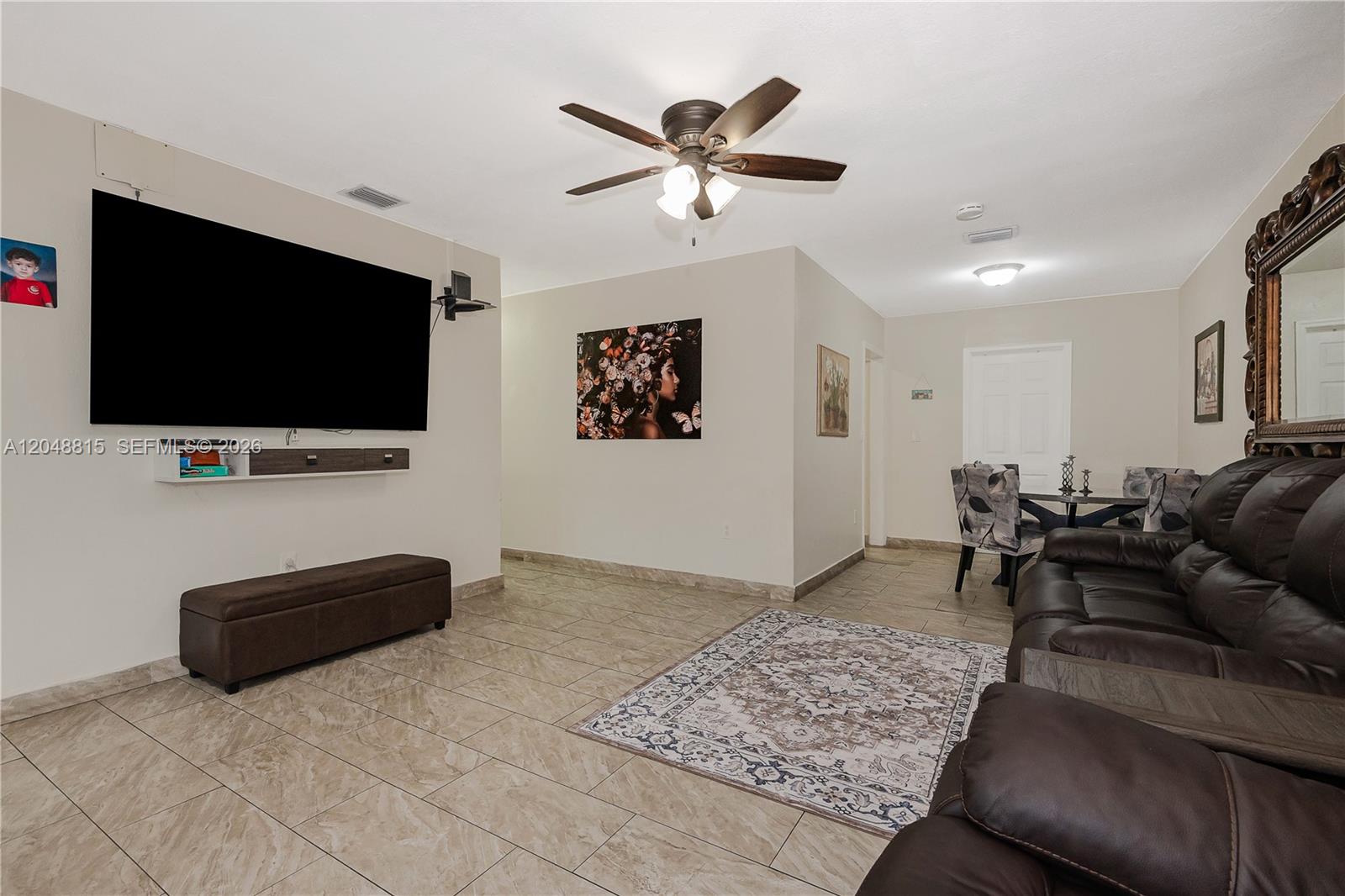 A living room features tile flooring, a large wall-mounted television, and a brown leather sofa — 750 NE 4th Pl, Hialeah FL 33010, HIALEAH, FL