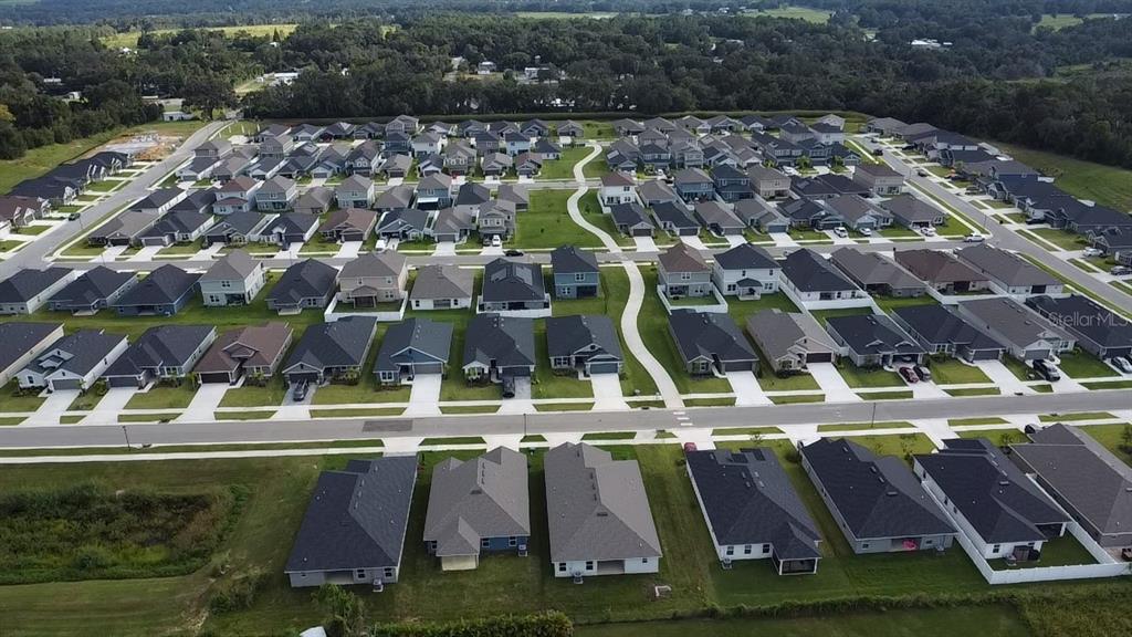 An aerial view shows a row of suburban houses bordering a grassy hill and park — 12984 KENT BRADLEY STREET, DADE CITY, FL