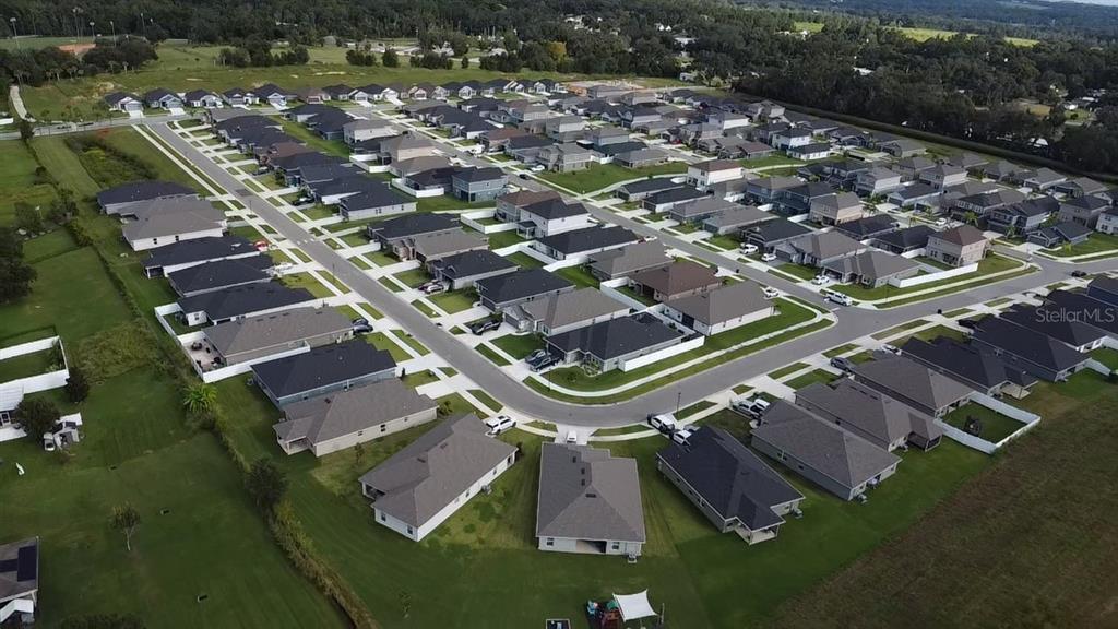 An aerial view shows a suburban neighborhood with rows of single-family homes and paved streets — 12984 KENT BRADLEY STREET, DADE CITY, FL