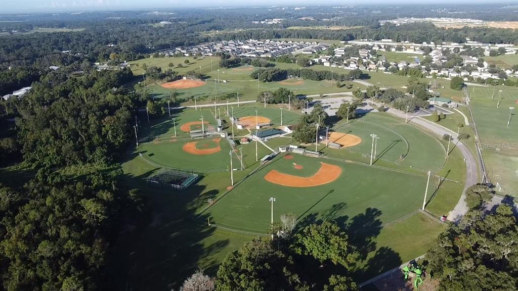 An aerial view shows a suburban neighborhood with many single-family homes and paved streets — 12984 KENT BRADLEY STREET, DADE CITY, FL