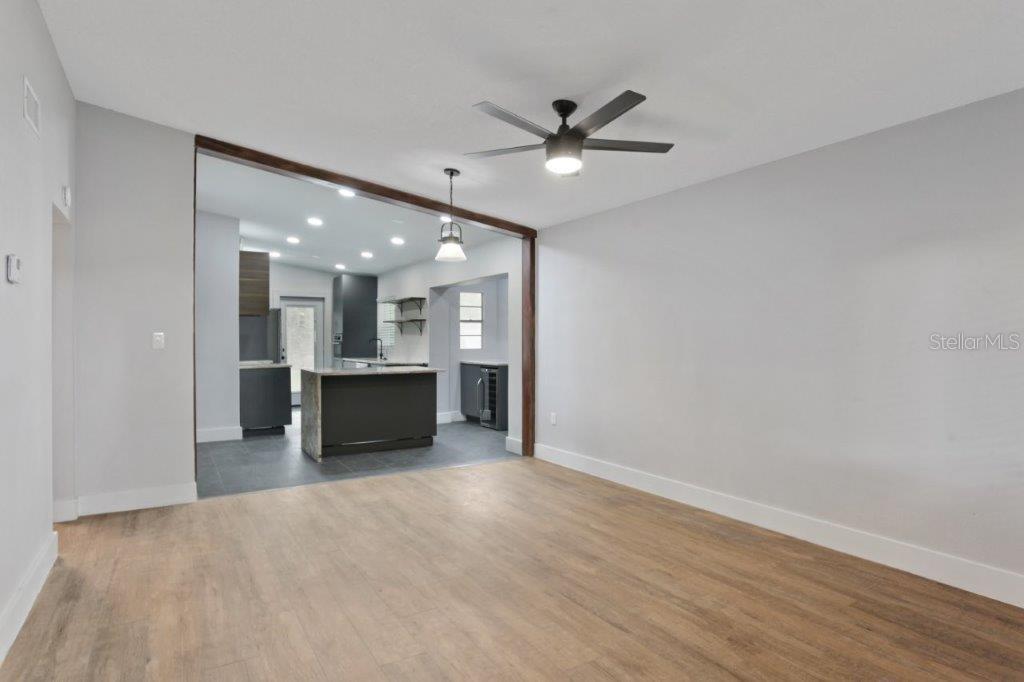 A living room with wood-look flooring opens into a modern kitchen with dark cabinetry — 3417 SE TENNESSEE TERRACE, ORLANDO, FL