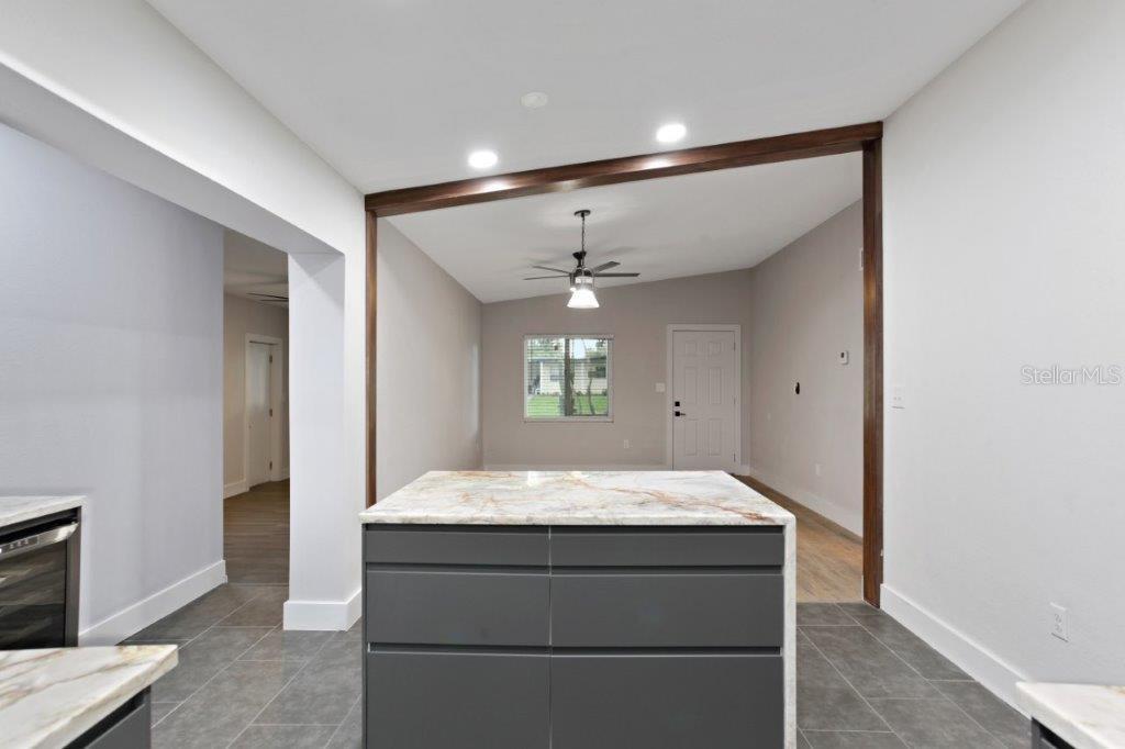 A kitchen island with a marble countertop sits in front of a living area — 3417 SE TENNESSEE TERRACE, ORLANDO, FL