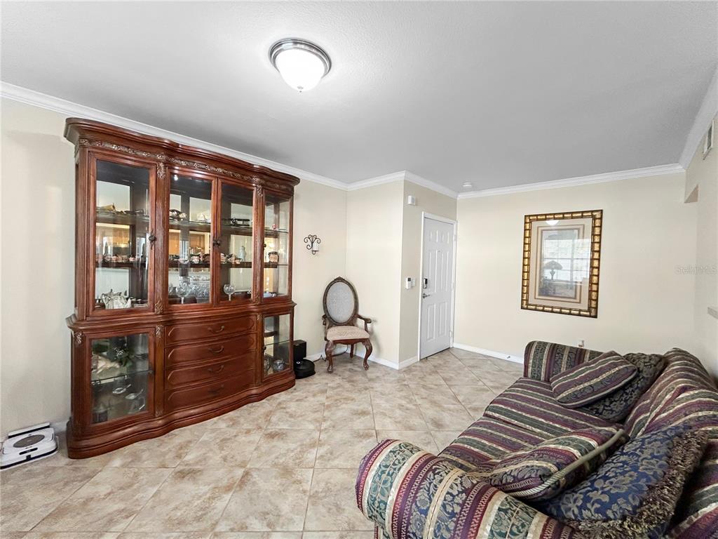 A living room features tile flooring, a large wooden china cabinet, and a striped sofa — 1025 VILLAGIO CIRCLE UNIT 101, SARASOTA, FL