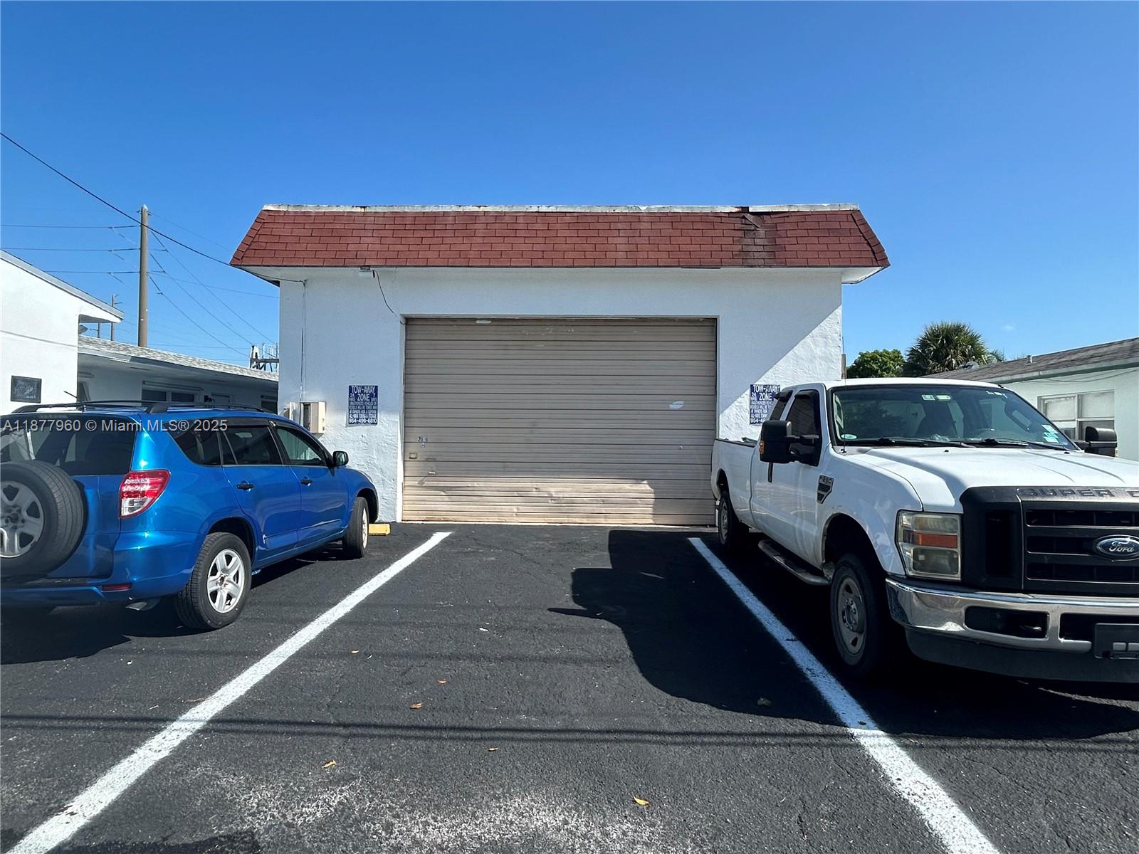 A white garage building with a brown shingled roof sits between two parked vehicles — 2028 Buchanan St, Hollywood FL 33020, HOLLYWOOD, FL