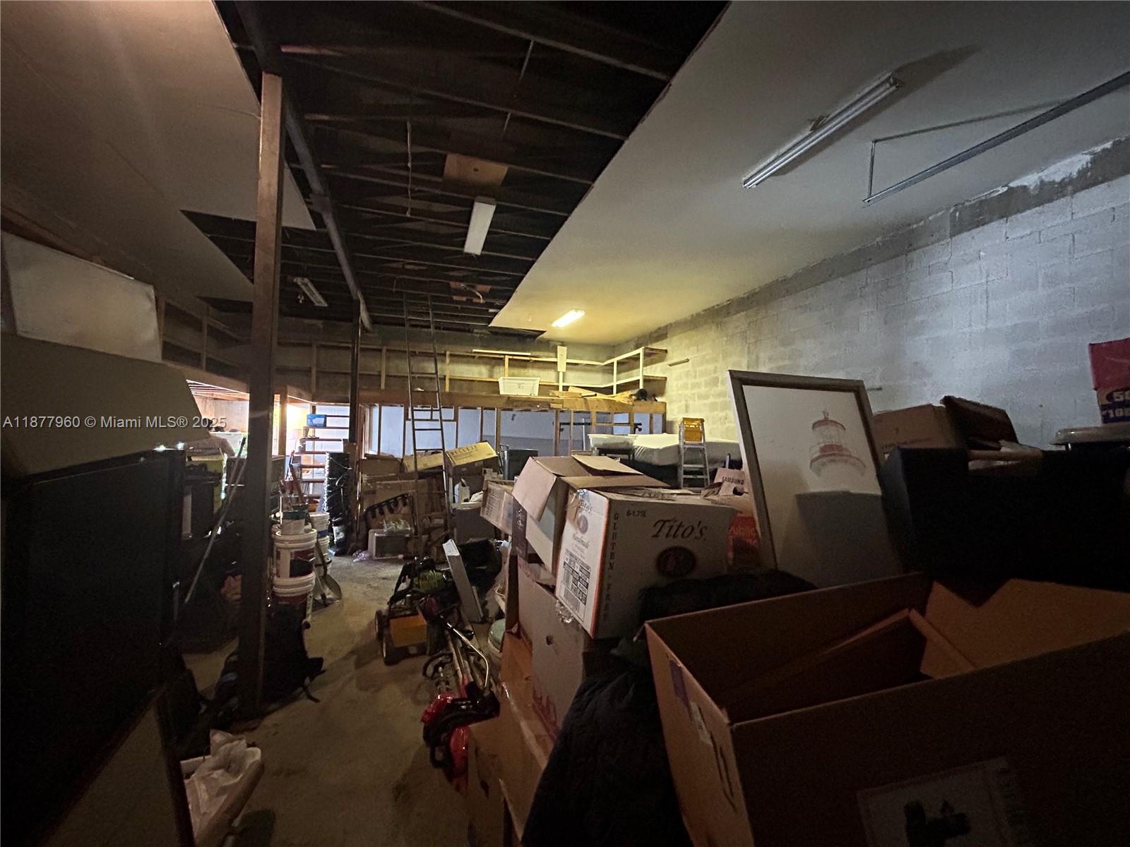 An unfinished storage room or garage contains stacked cardboard boxes and exposed ceiling rafters — 2028 Buchanan St, Hollywood FL 33020, HOLLYWOOD, FL