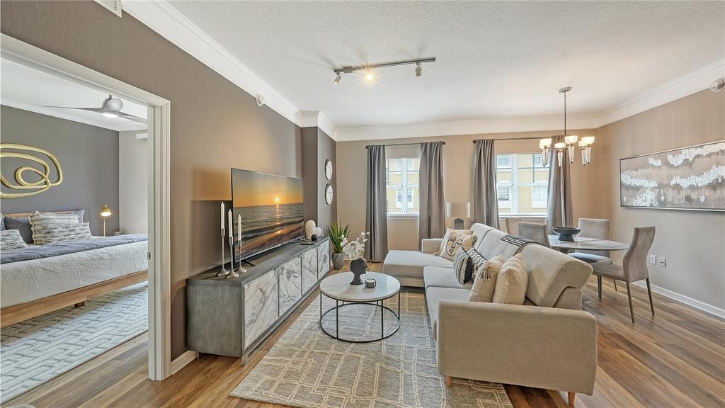 A living room with a sectional sofa, marble-topped media console, and an adjacent bedroom — 1064 N TAMIAMI TRAIL UNIT 1522, SARASOTA, FL