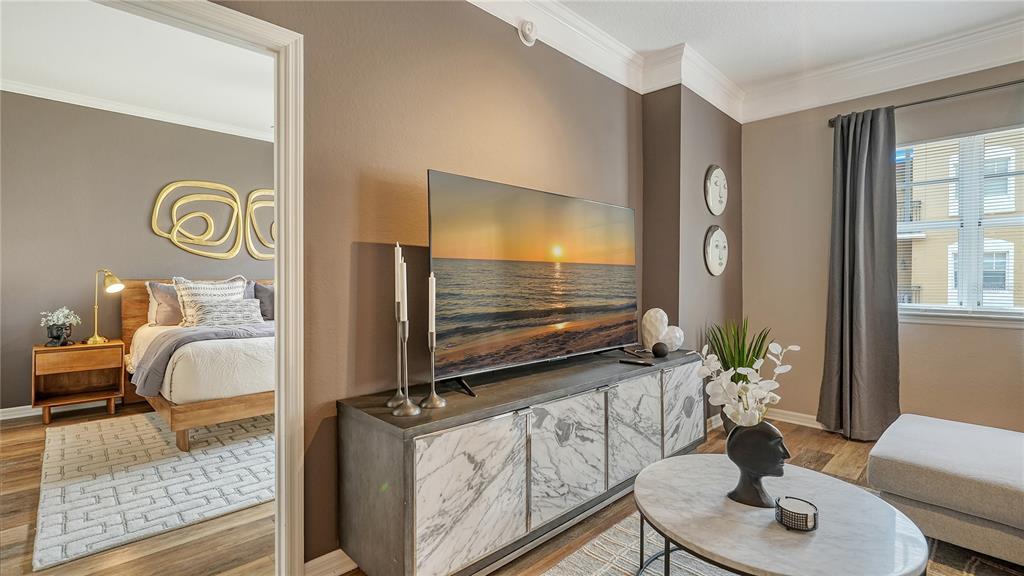 A living room with a marble-fronted media console faces a doorway leading to a bedroom — 1064 N TAMIAMI TRAIL UNIT 1522, SARASOTA, FL