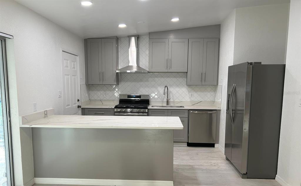 A kitchen features gray cabinets, stainless steel appliances, and a white marble-look countertop island — 1838 COLTON DRIVE, ORLANDO, FL