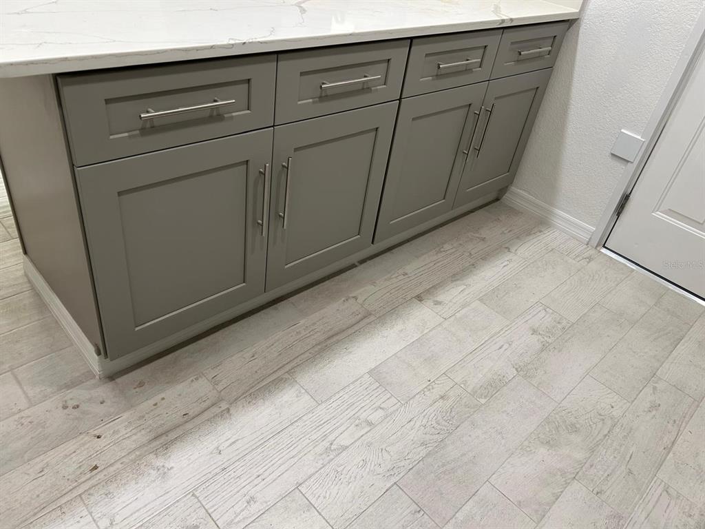 A gray kitchen cabinet base with a white marble countertop sits on light wood-look flooring — 1838 COLTON DRIVE, ORLANDO, FL