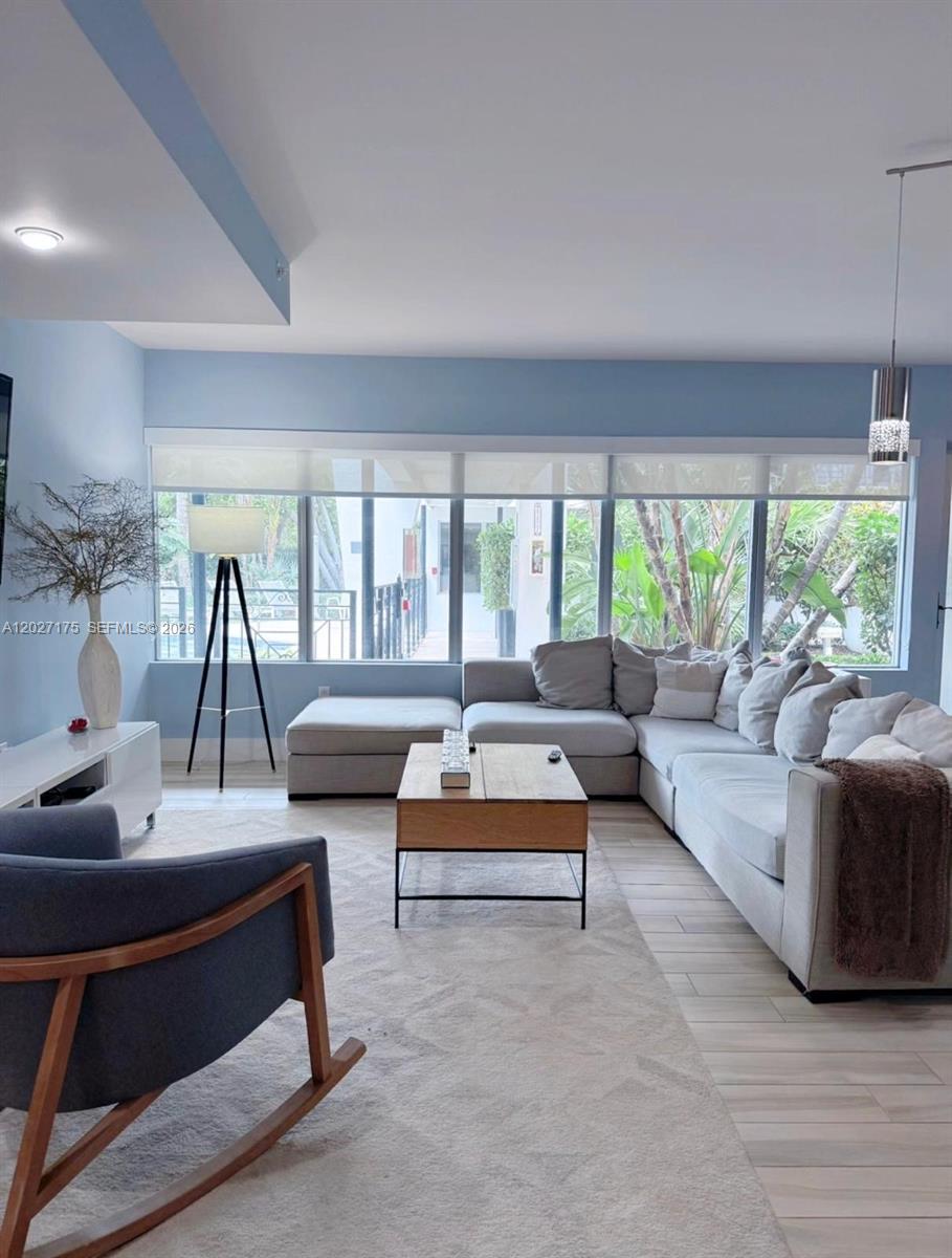 A living room features a large sectional sofa, a rocking chair, and floor-to-ceiling windows — 2135 Washington Ct # 7, Miami Beach FL 33139, MIAMI BEACH, FL