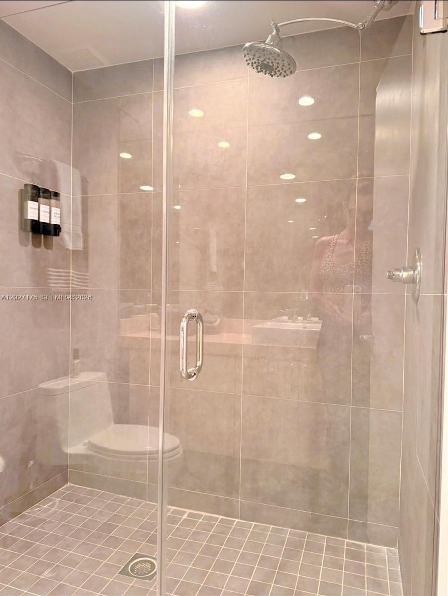 A glass-enclosed walk-in shower with beige tile walls and a toilet are visible — 2135 Washington Ct # 7, Miami Beach FL 33139, MIAMI BEACH, FL