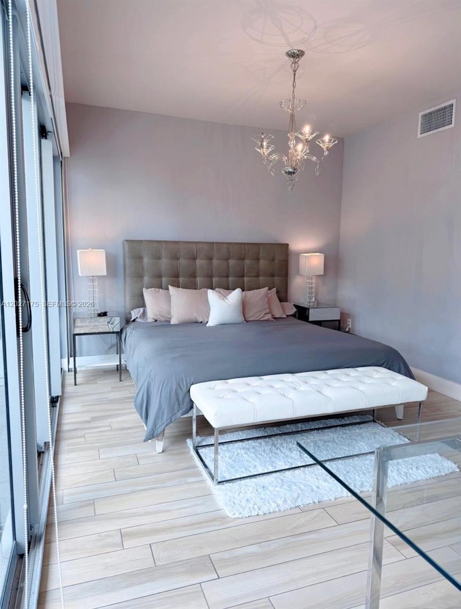 A bedroom features a tufted headboard, a white bench, and a crystal chandelier — 2135 Washington Ct # 7, Miami Beach FL 33139, MIAMI BEACH, FL